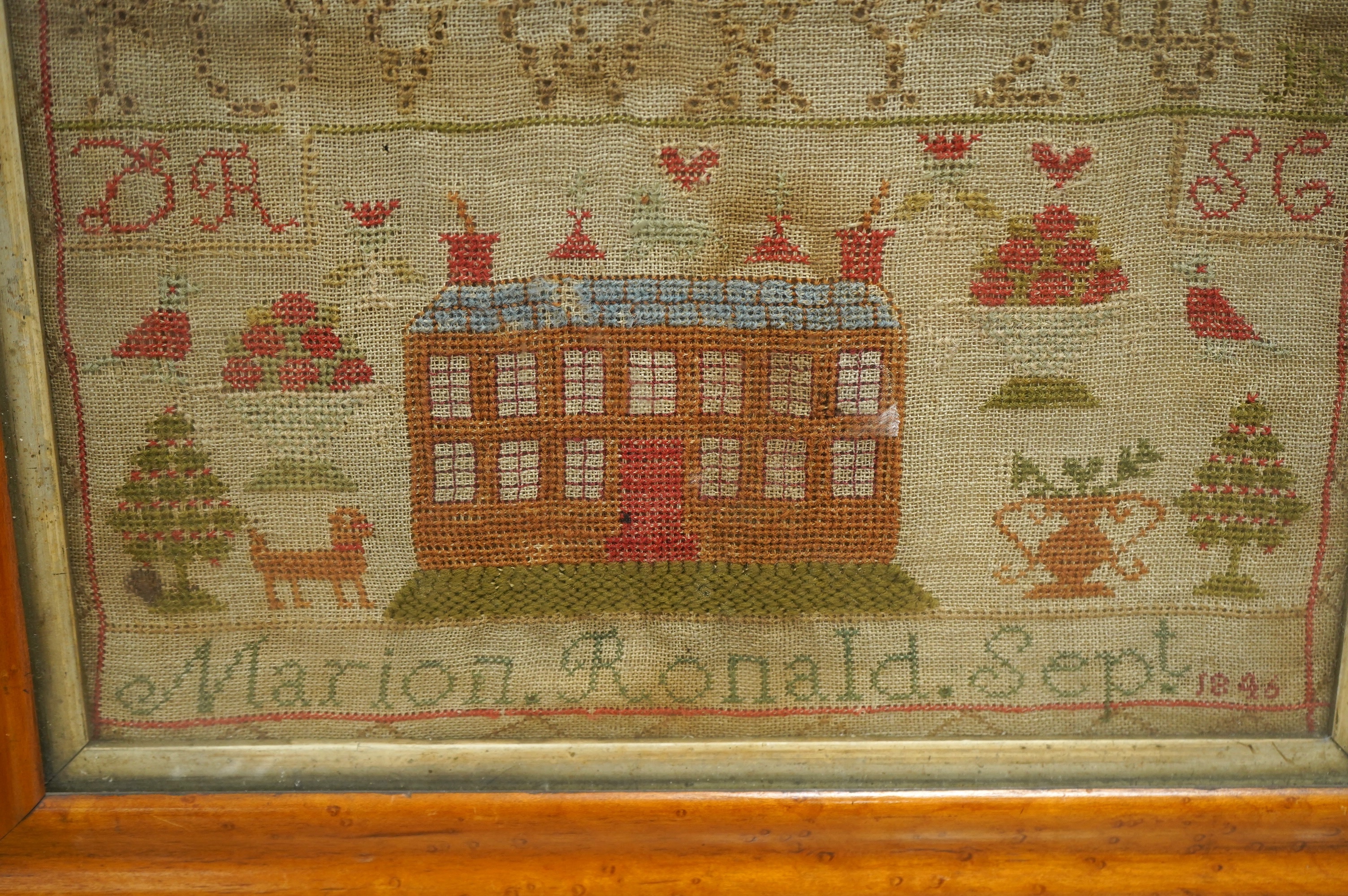 A 19th century sampler by Marion Ronald dated 1846, worked with various alphabets in cross stitch and buttonhole stitch, the lower section depicting a large thirteen windowed house surrounded by various spot motifs, a do